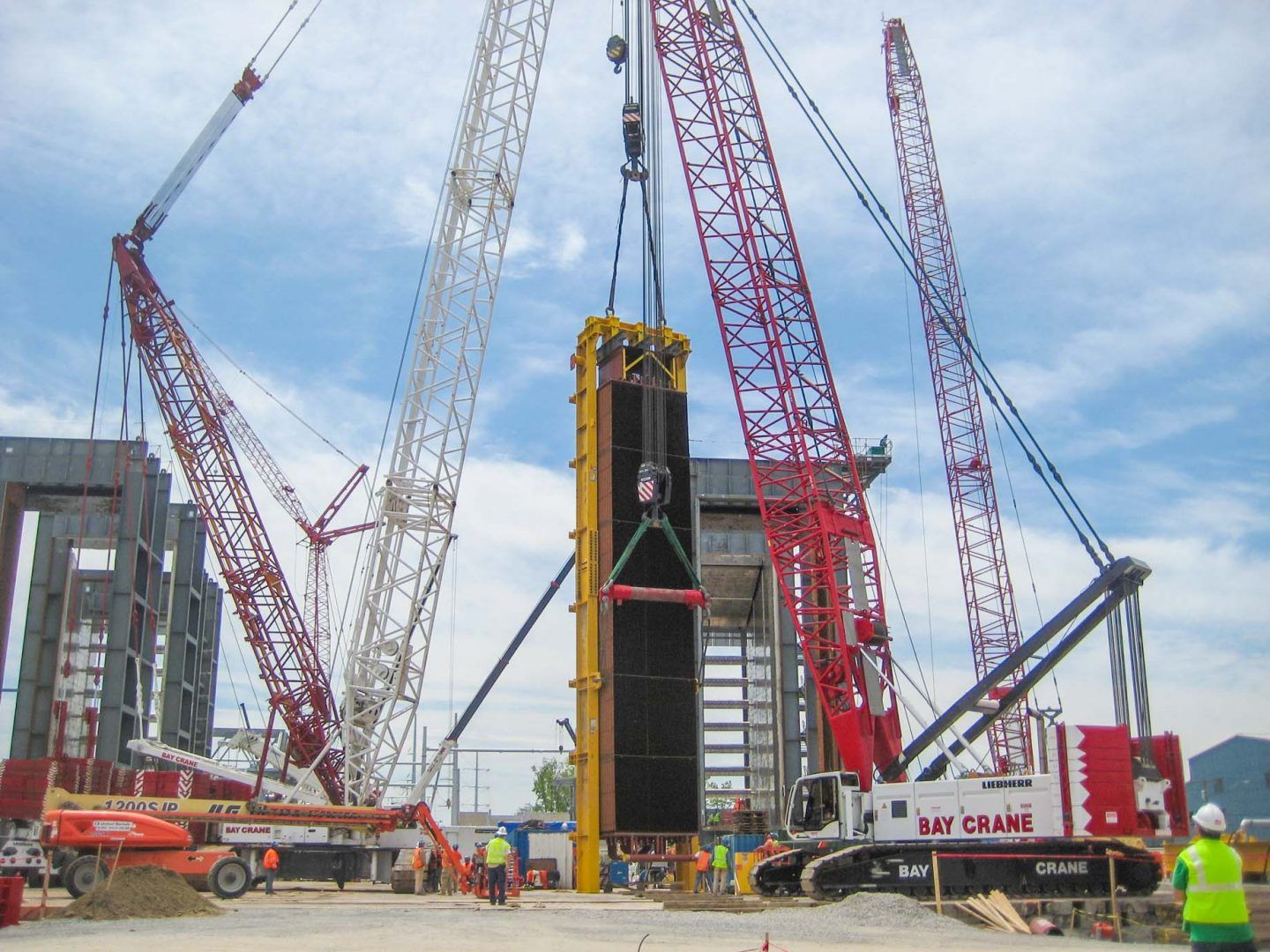 Bay Crane crews and a Liebherr crawler crane setting a large precast wall panel on an active jobsite